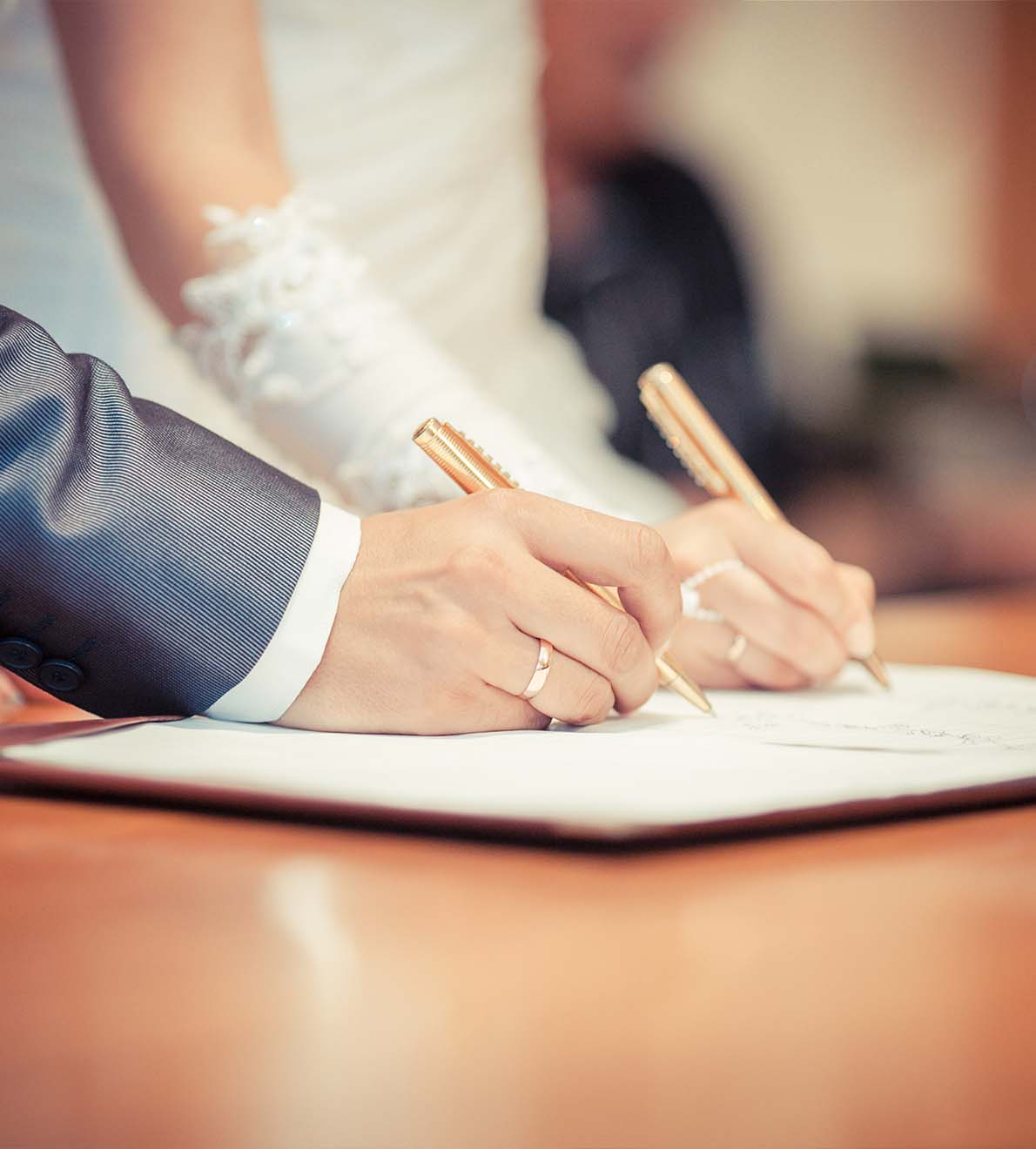 Image of a couple signing their wedding documents, illustrating the important step of legal paperwork in the wedding process, featured on Ash Reynolds' site.