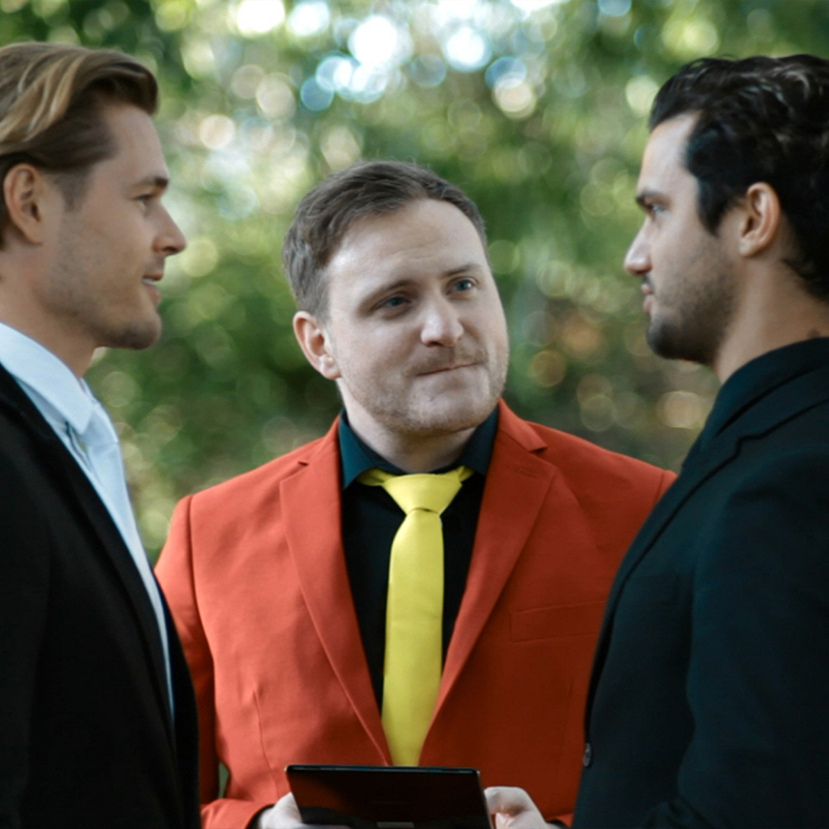 Ash Reynolds officiating a same-sex wedding, dressed in a vibrant suit, showcasing his inclusive and colorful approach to modern celebrancy.